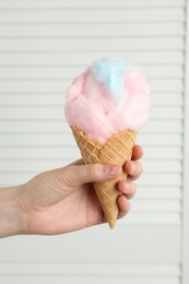 Photo of Woman holding waffle cone with cotton candy, closeup