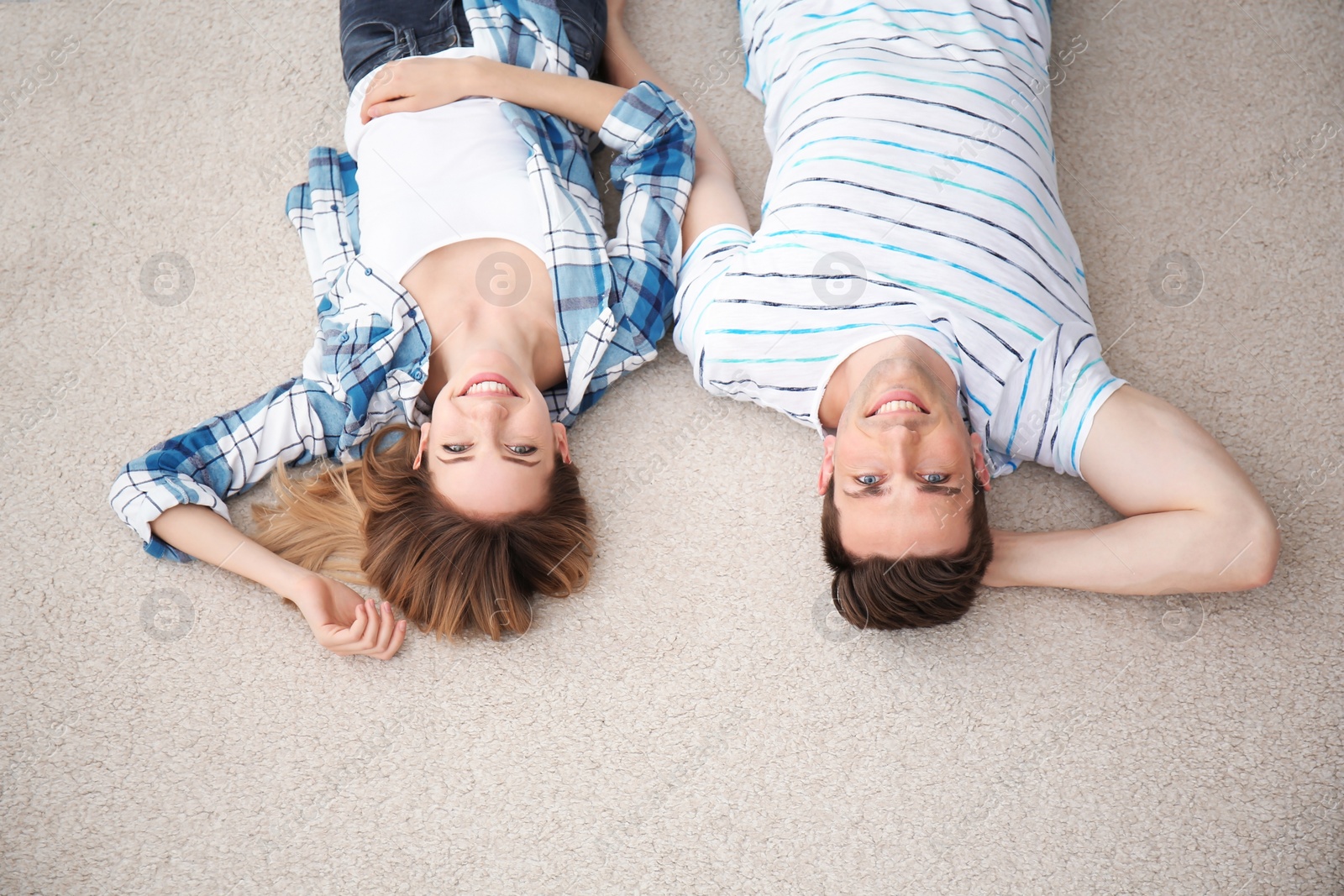 Photo of Lovely young couple lying on cozy carpet at home