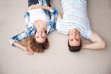 Lovely young couple lying on cozy carpet at home