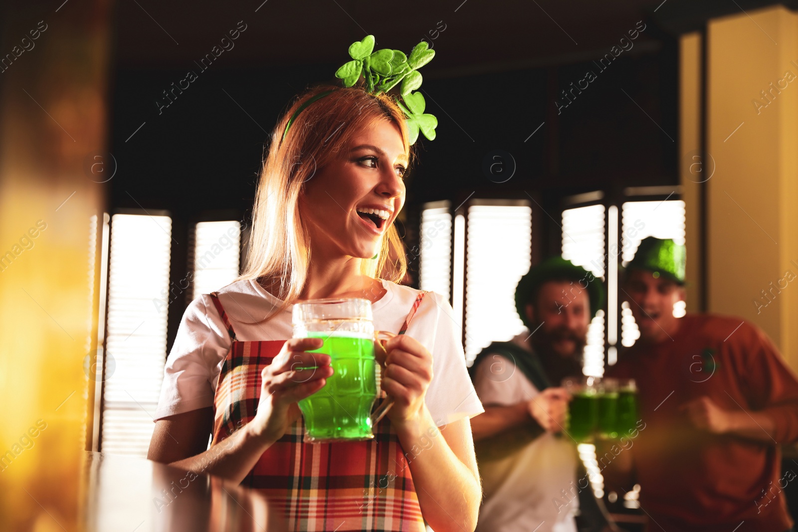 Photo of Young woman with glass of green beer in pub. St. Patrick's Day celebration