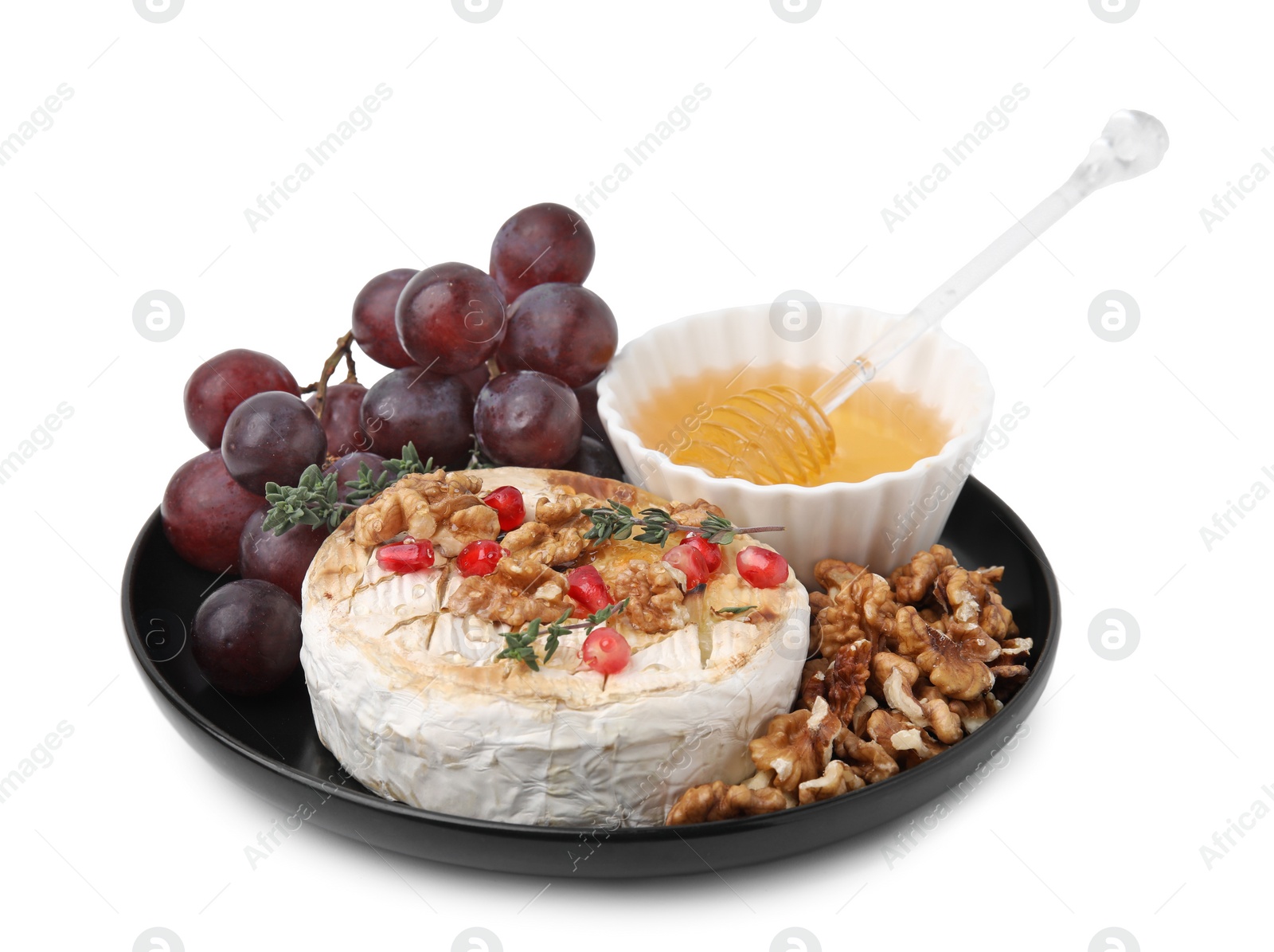 Photo of Plate with tasty baked camembert, honey, grapes, walnuts and pomegranate seeds isolated on white