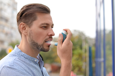 Image of Man using asthma inhaler outdoors. Health care
