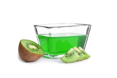 Slices of kiwi and tasty jelly dessert in glass bowl on white background