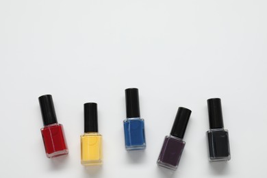 Photo of Nail polishes on white background, flat lay. Space for text