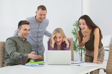 Photo of Group of colleagues laughing together in office
