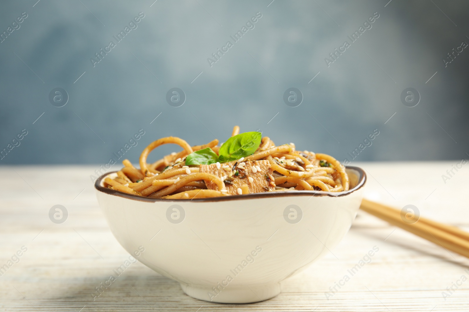 Photo of Tasty buckwheat noodles with meat in bowl on white wooden table