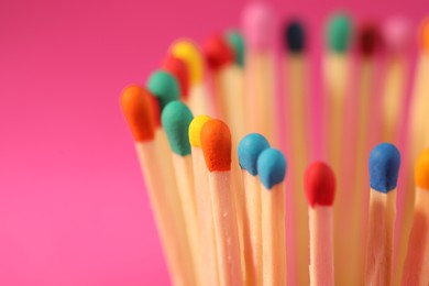 Photo of Matches with colorful heads on pink background, closeup