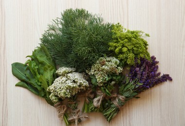 Bunches of different beautiful dried flowers and herbs on white wooden table, flat lay