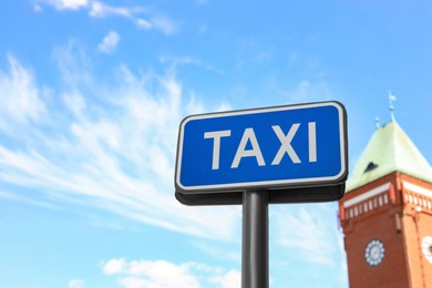 Post with TAXI sign against blue sky, low angle view