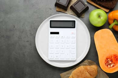 Photo of Calculator and food products on dark grey table, flat lay with space for text. Weight loss concept