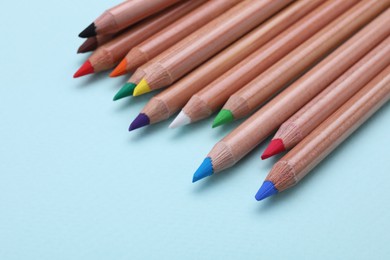 Photo of Colorful pastel pencils on light blue background, closeup with space for text. Drawing supplies