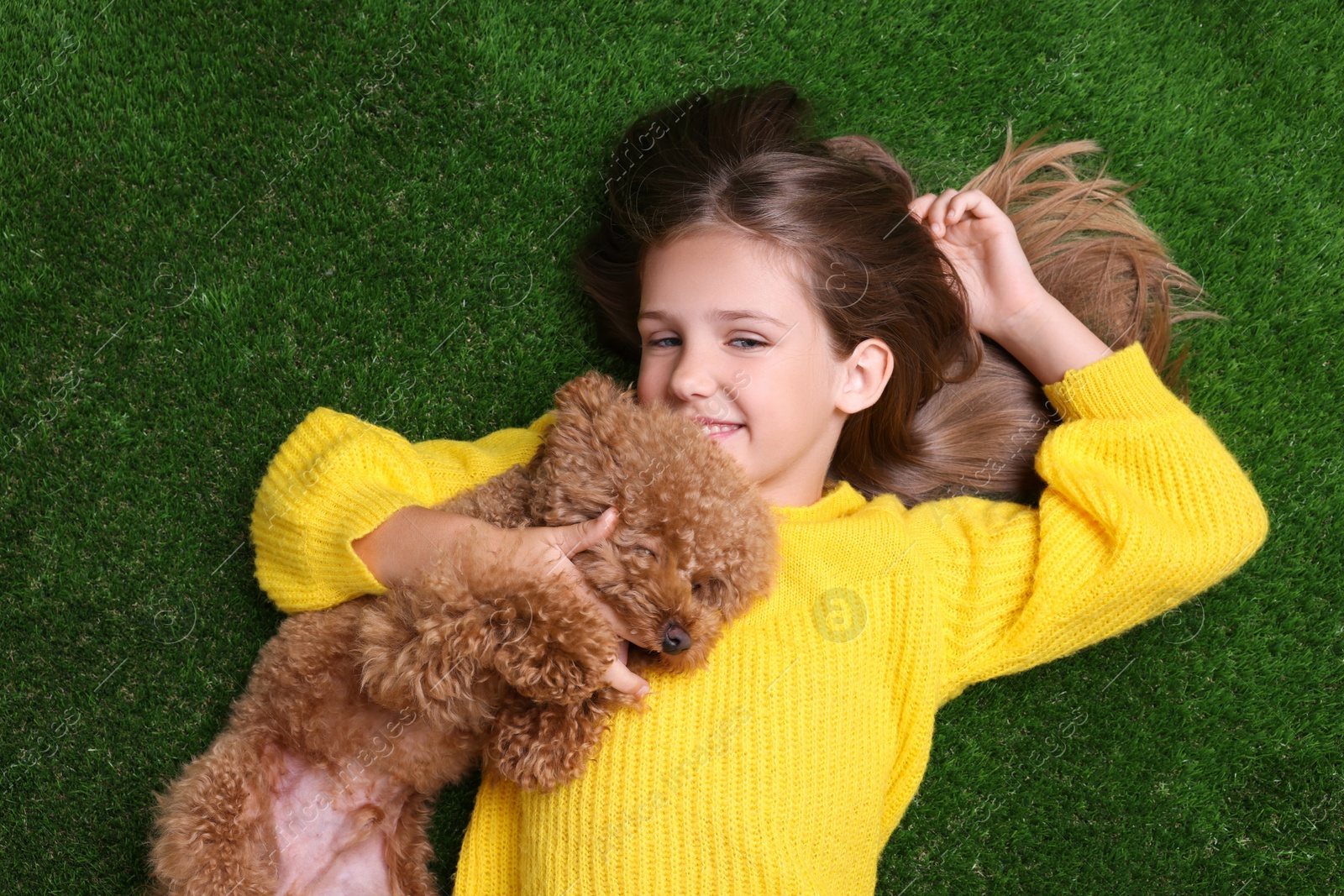 Photo of Little child with cute puppy on green grass, top view. Lovely pet