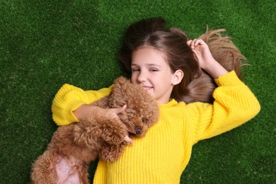 Photo of Little child with cute puppy on green grass, top view. Lovely pet