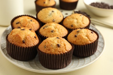 Photo of Delicious sweet muffins with chocolate chips on beige table, closeup