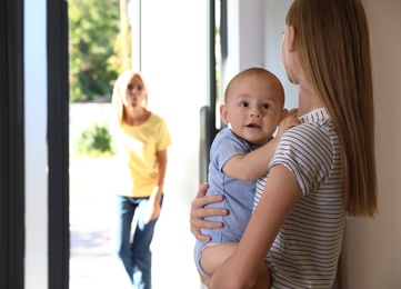 Photo of Mother leaving her baby with teen nanny at home. Space for text