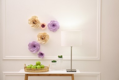 Console table near wall with floral decor in room. Interior design