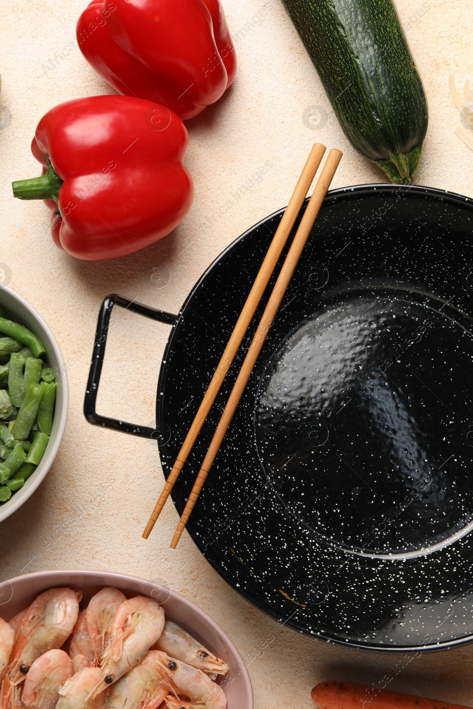 Photo of Black wok, chopsticks and products on color table, flat lay