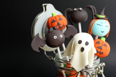 Photo of Delicious Halloween themed cake pops on black background, closeup