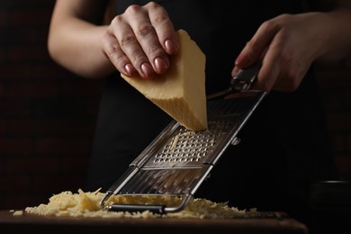 Photo of Woman grating cheese at wooden table, closeup