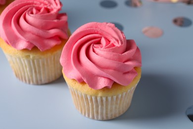 Photo of Delicious cupcakes with bright cream on light background, closeup