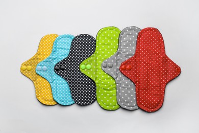 Many reusable cloth menstrual pads on white background, flat lay