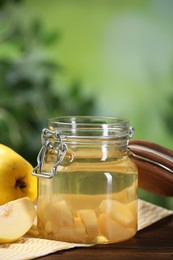 Delicious quince drink and fresh fruits on wooden table against blurred background, closeup