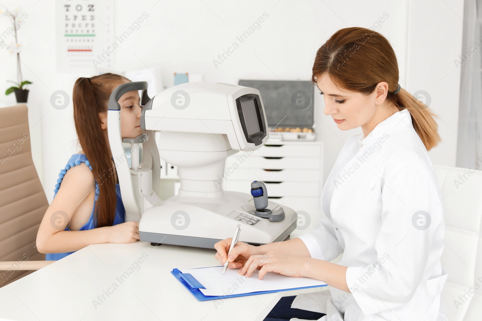 Photo of Ophthalmologist examining little girl in clinic