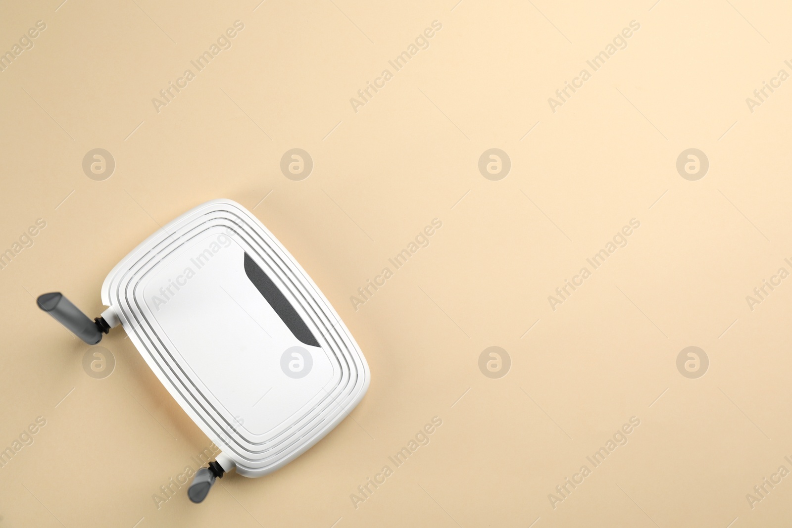 Photo of Modern Wi-Fi router on beige background, top view. Space for text