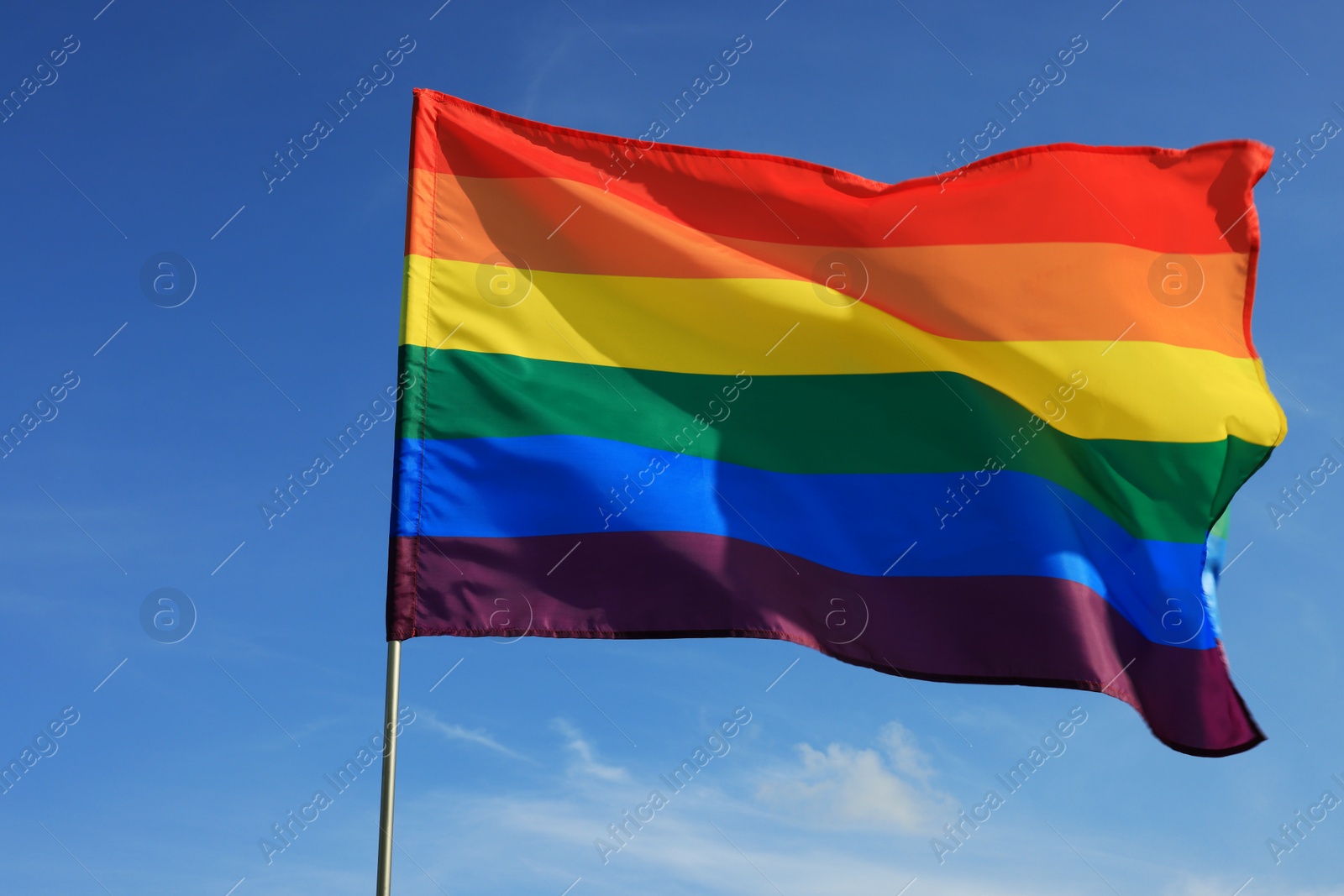 Photo of Bright LGBT flag fluttering against blue sky