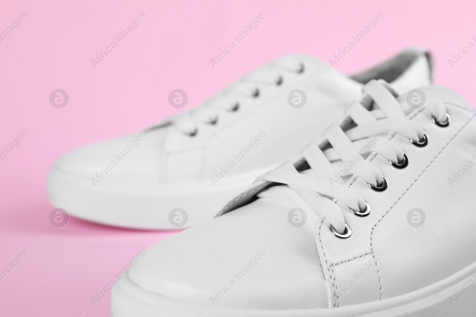 Photo of Pair of stylish white sneakers on pink background, closeup