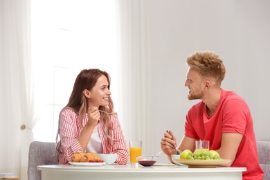 Happy young couple having breakfast at table in room