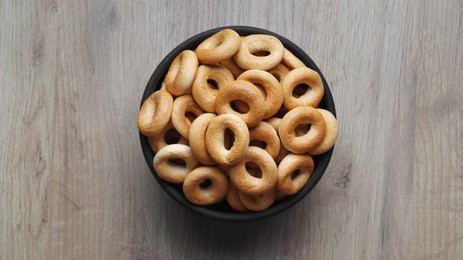 Photo of Bowl of tasty dry bagels (sushki) on wooden table, top view