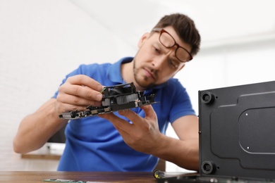 Photo of Male technician repairing computer at table indoors