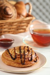 Photo of Tasty freshly baked spiral pastry on white table, closeup. Space for text