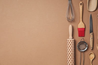 Set of modern cooking utensils on brown background, flat lay. Space for text