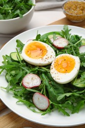 Photo of Delicious salad with boiled egg, vegetables and arugula on board, closeup