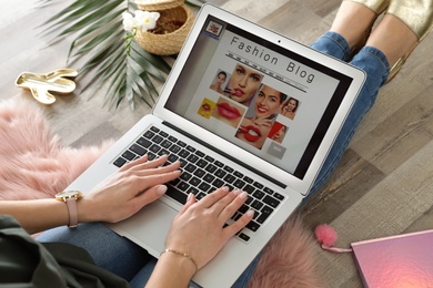 Photo of Woman holding laptop with open fashion blogger site on floor, closeup