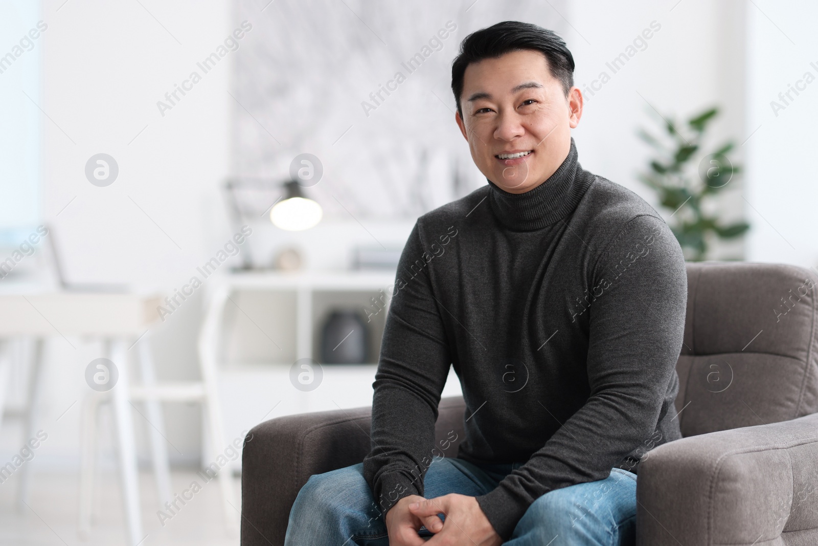 Photo of Portrait of smiling businessman on armchair in office. Space for text