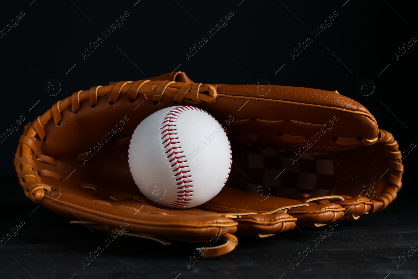 Photo of Catcher's mitt and baseball ball on black background. Sports game