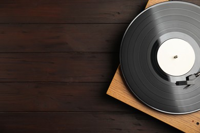 Photo of Turntable with vintage vinyl record on wooden background, top view. Space for text