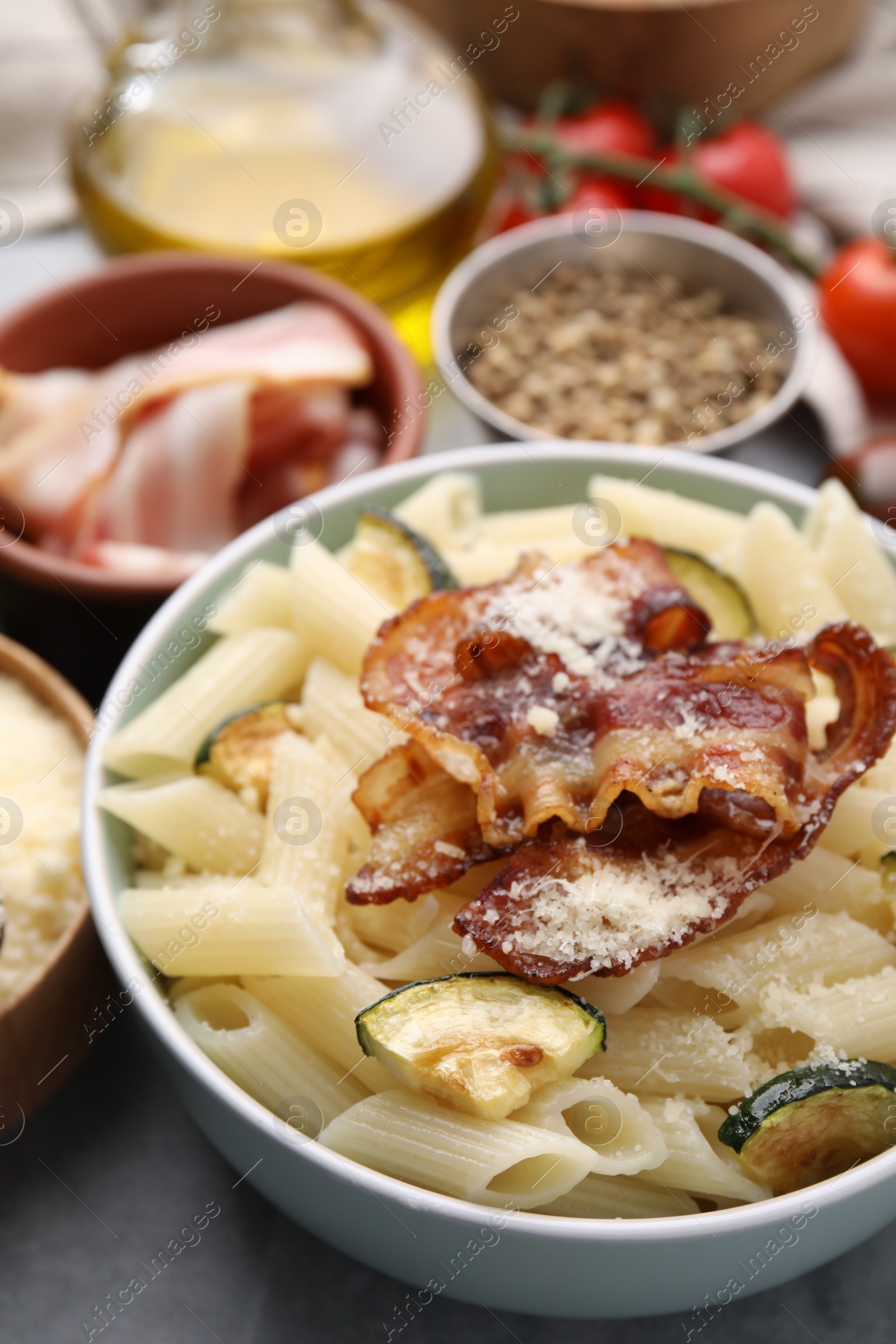 Photo of Tasty pasta with bacon and cheese on grey table, closeup