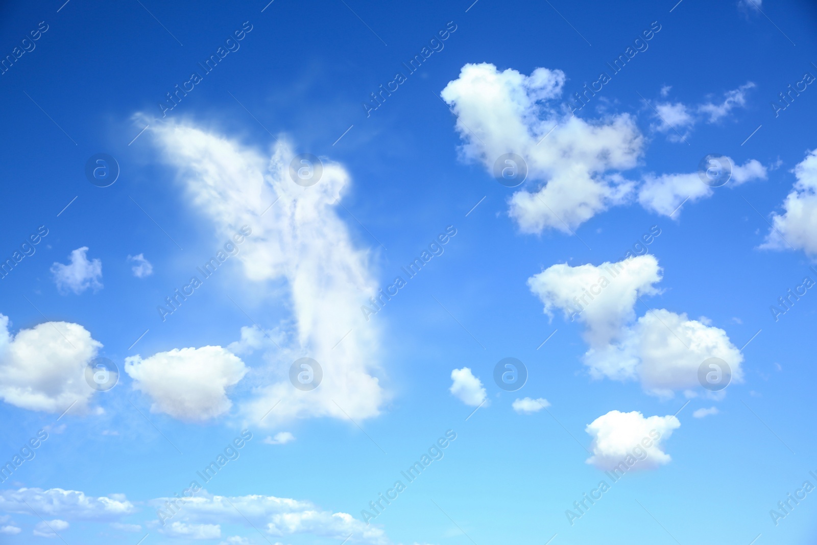 Image of Silhouette of angel made of clouds in blue sky 