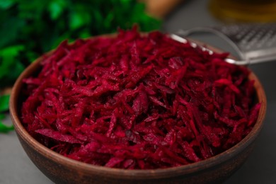 Photo of Grated red beet in bowl on table, closeup