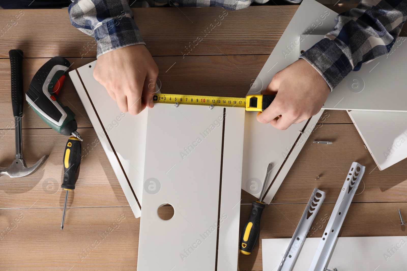 Photo of Man assembling furniture at wooden table, closeup