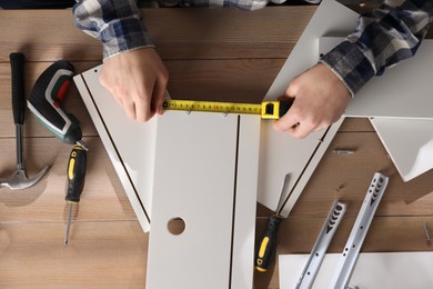 Man assembling furniture at wooden table, closeup