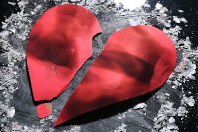 Photo of Halves of torn paper heart and ash on dark background