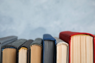 Photo of Stack of hardcover books on light blue background, closeup. Space for text