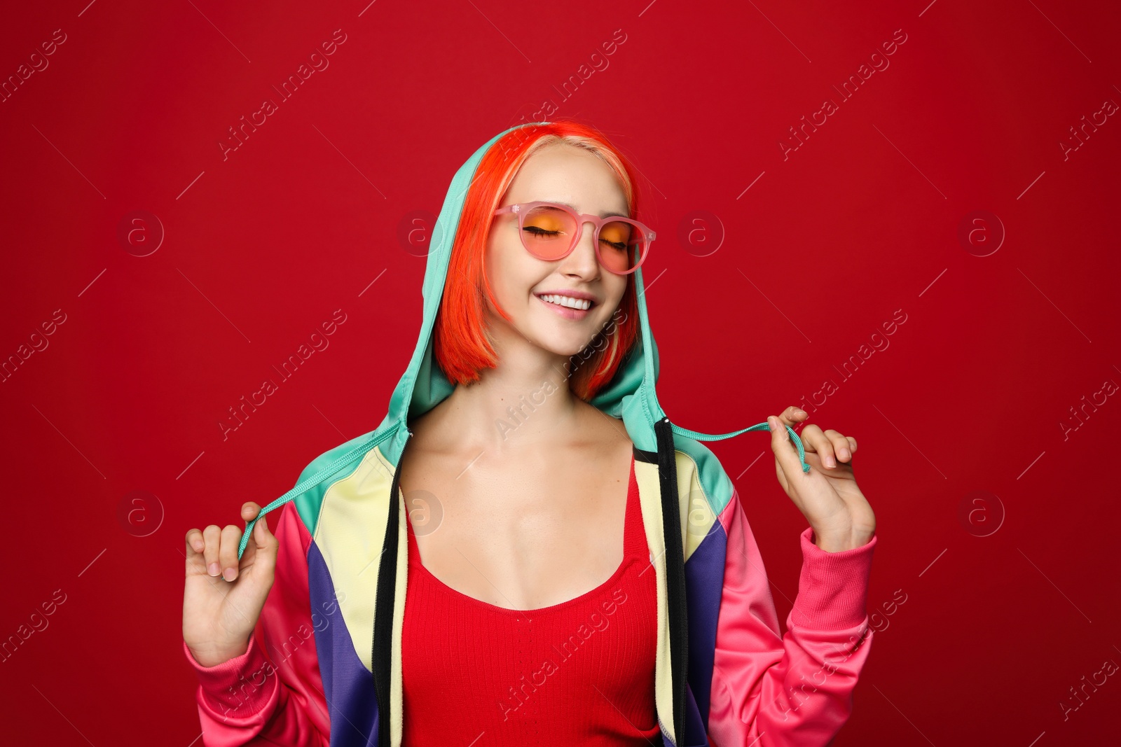 Photo of Beautiful young woman with bright dyed hair on red background