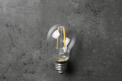 Vintage lamp bulb on grey stone surface, top view