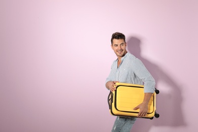 Photo of Young man with suitcase on color background. Space for text